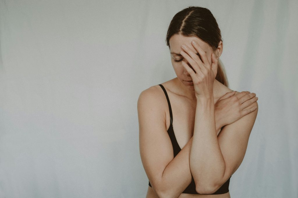 A woman in contemplation with a hand on her face, expressing emotional distress.