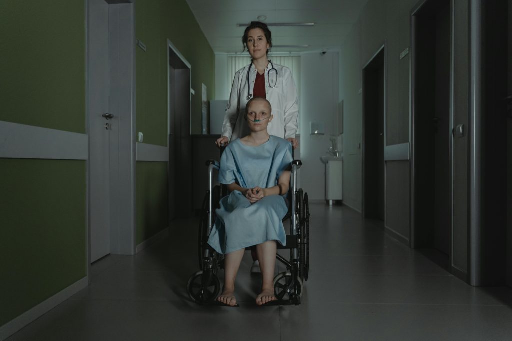 Doctor assisting female patient in wheelchair in dimly lit hospital hallway.