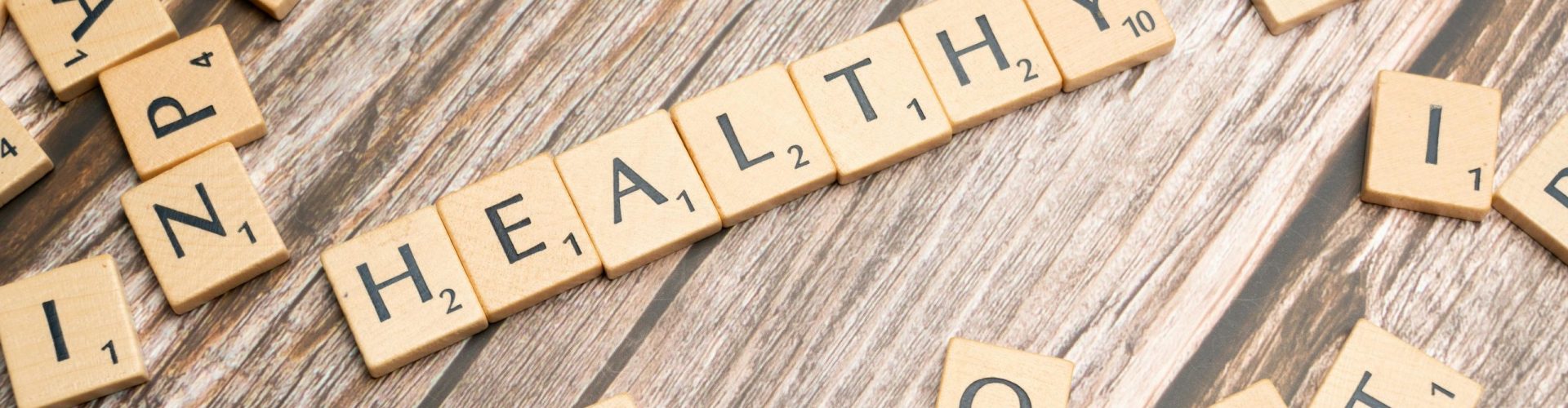 pexels-photo-19825315-19825315 Wooden letter tiles arranged on a wooden surface spelling out 'healthy', symbolizing wellness.